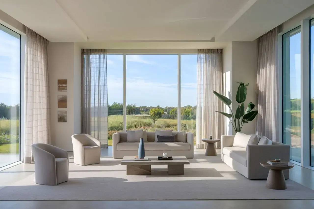 Un salon moderne et lumineux avec de grandes baies vitrées donnant sur une vue verdoyante.