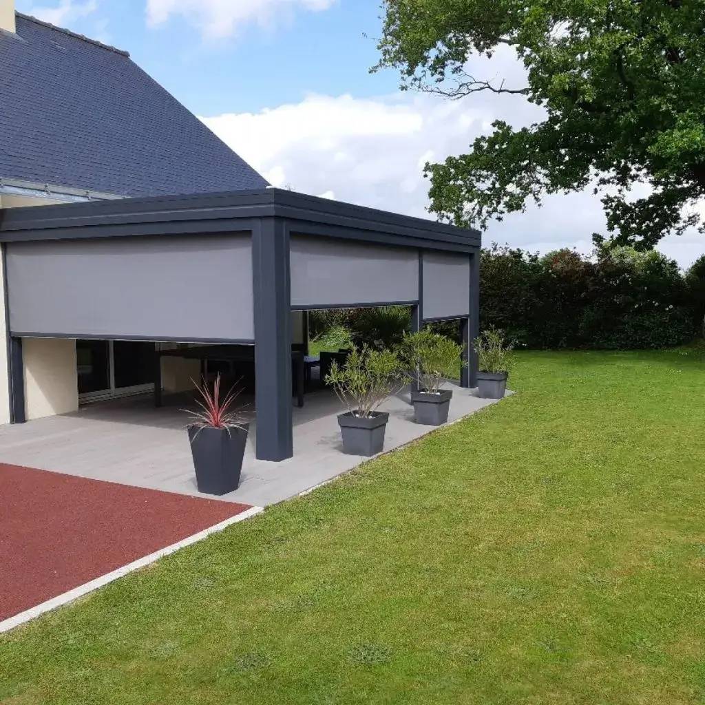 Une terrasse extérieure moderne avec pergola et stores intégrés, entourée de pots de plantes et d'un jardin verdoyant.