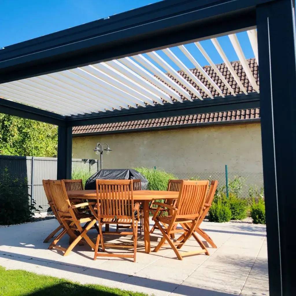 Une pergola moderne avec des lames ouvertes ombrage un ensemble de mobilier de jardin en bois, offrant un espace convivial en plein air.