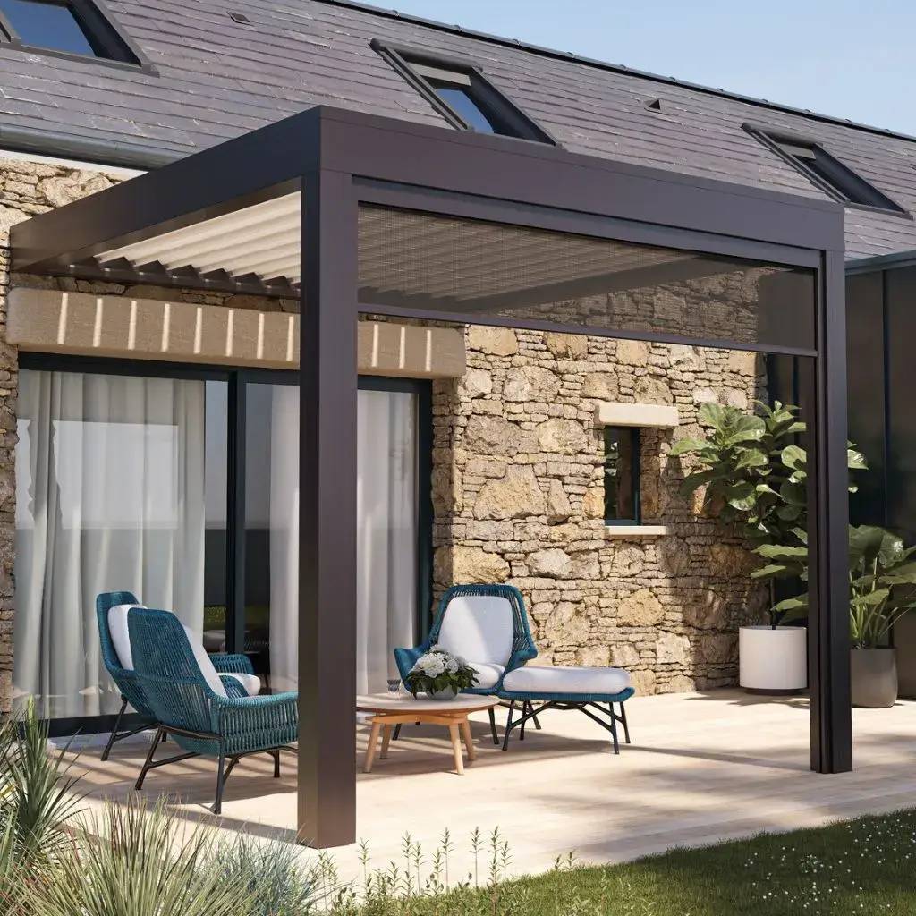 Une élégante terrasse abritée par une pergola moderne en métal, avec des fauteuils et un espace détente devant une maison en pierre.