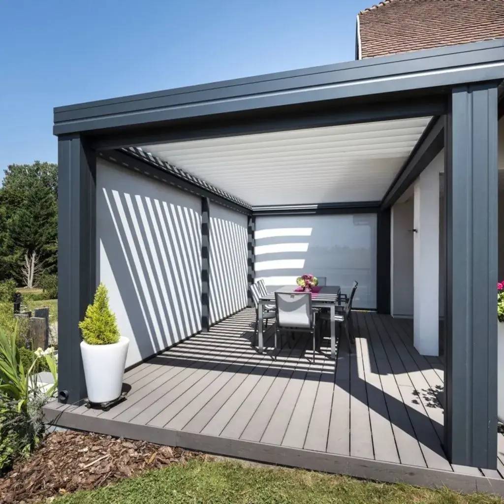 Une pergola moderne avec un toit lames orientables couvre une terrasse équipée d'une table à manger entourée de chaises.