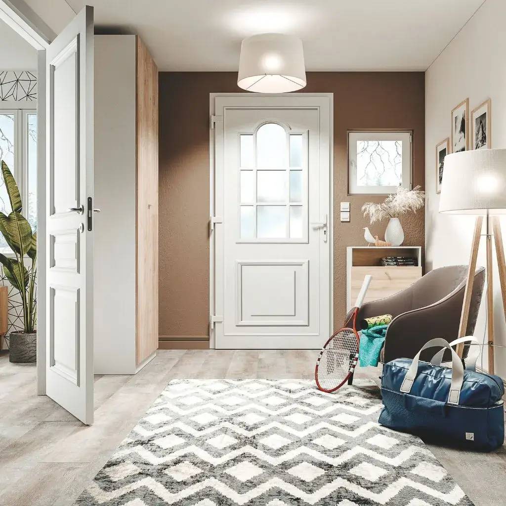Un hall d'entrée moderne et lumineux avec une porte blanche, des murs marron, et des accessoires de sport posés sur un tapis géométrique