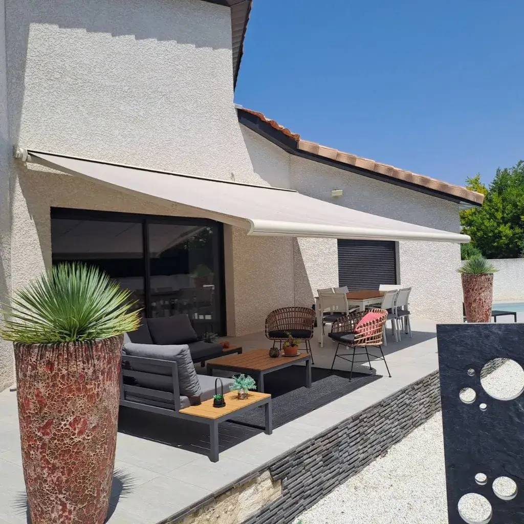Une terrasse moderne et ombragée, aménagée avec des meubles de jardin élégants et des plantes en pot.