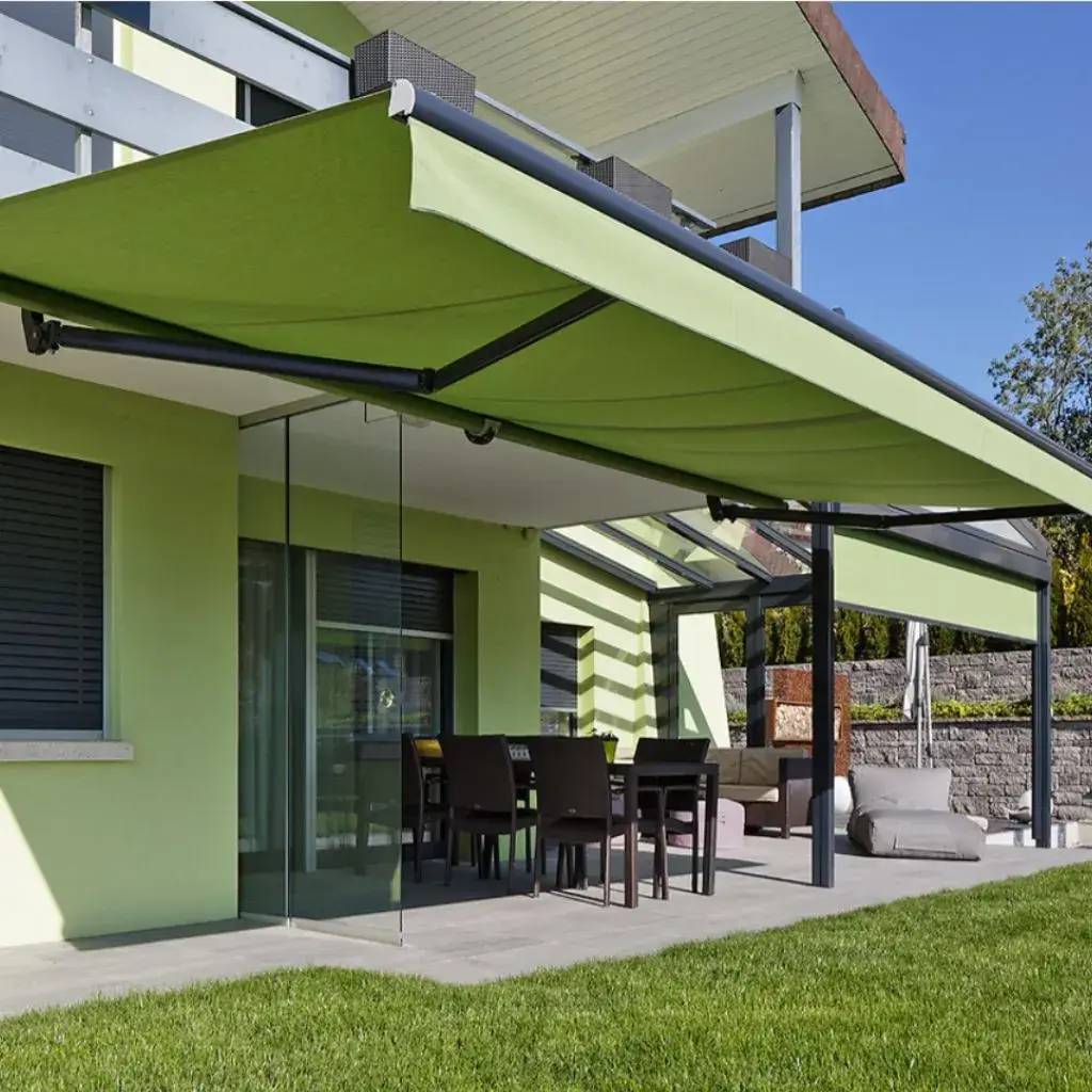 Une terrasse moderne avec un store vert et une salle à manger extérieure protégée par des baies vitrées.