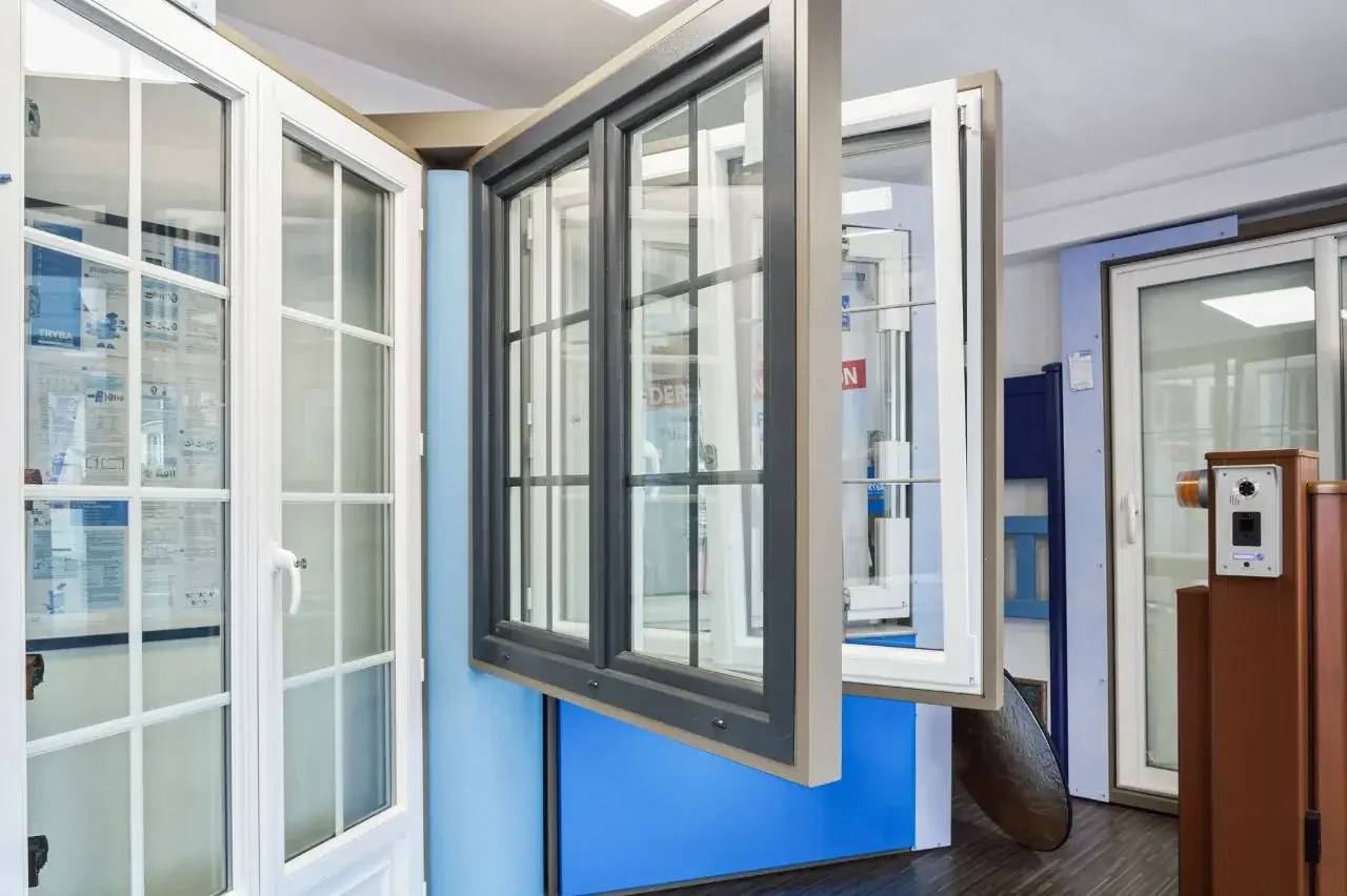 Cette image montre des fenêtres modernes à cadre noir et blanc dans un showroom, mettant en avant plusieurs styles et mécanismes d'ouverture.
