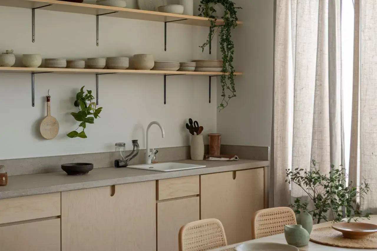 Cuisine moderne et minimaliste avec des étagères ouvertes, des plantes vertes et de la vaisselle en céramique.
