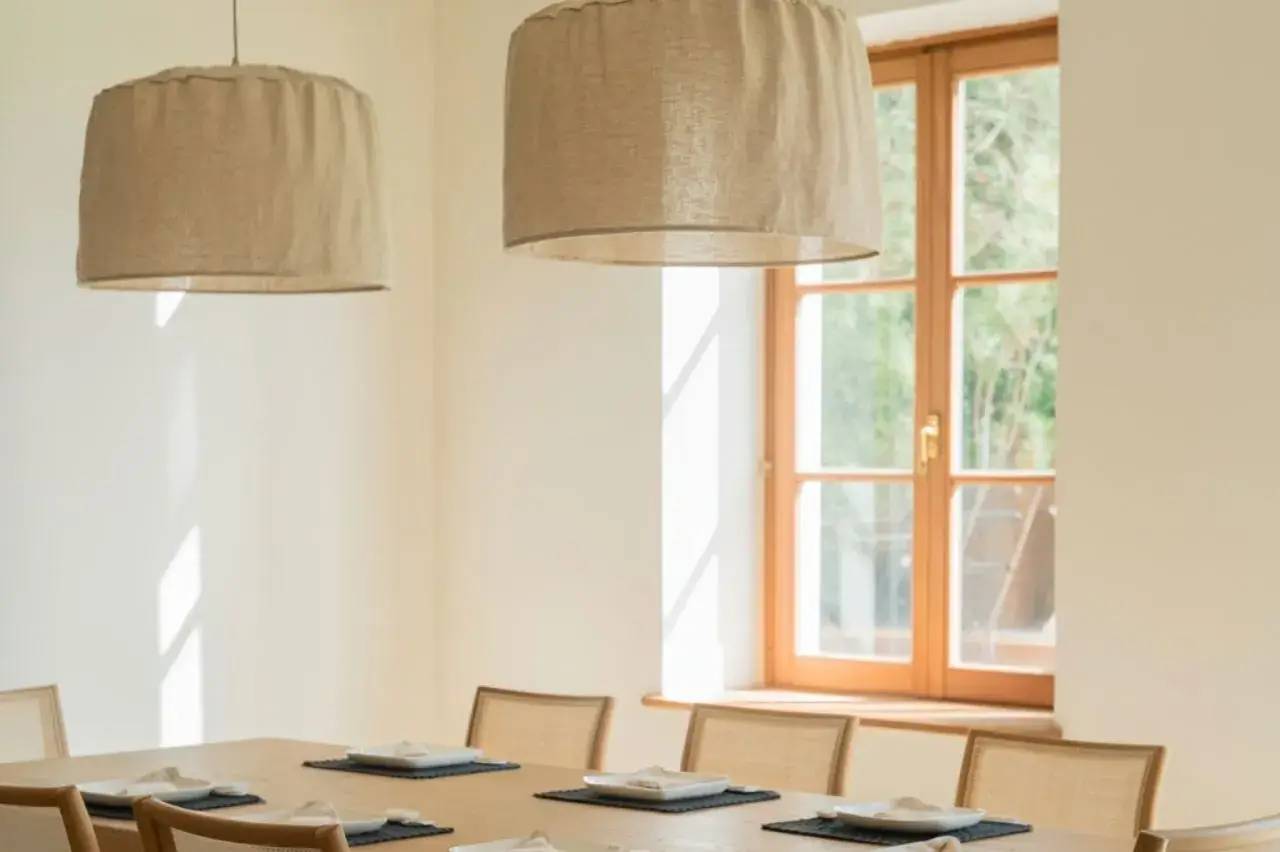 Salle à manger lumineuse avec un design minimaliste, comportant une table en bois, des chaises assorties, et de grandes suspensions beige