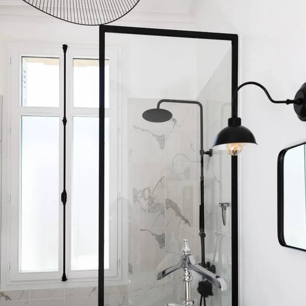 Salle de bain élégante avec douche à l'italienne, paroi vitrée et éléments noirs modernes.