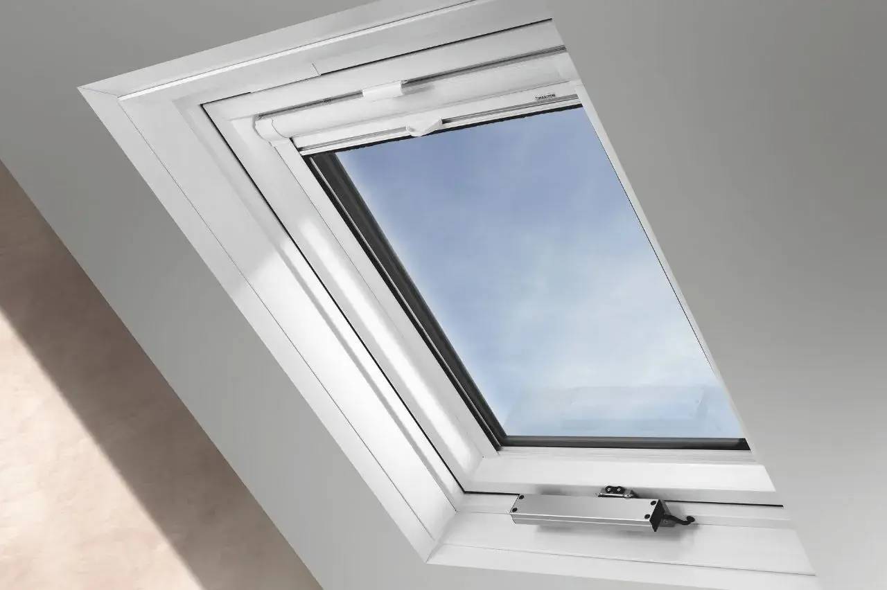 Fenêtre de toit moderne avec un cadre blanc, s'ouvrant sur un ciel bleu dégagé.
