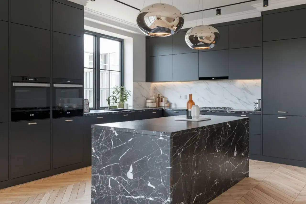 Une cuisine moderne avec des armoires noires, un comptoir en marbre sombre et deux suspensions métalliques brillantes.