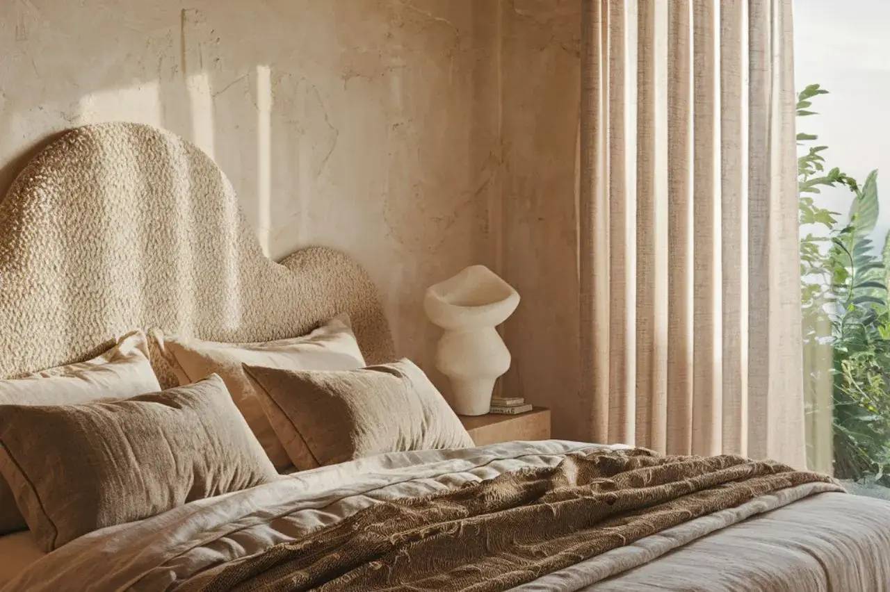 Une chambre lumineuse avec une décoration chaleureuse et naturelle, incluant un lit douillet et des rideaux beiges.