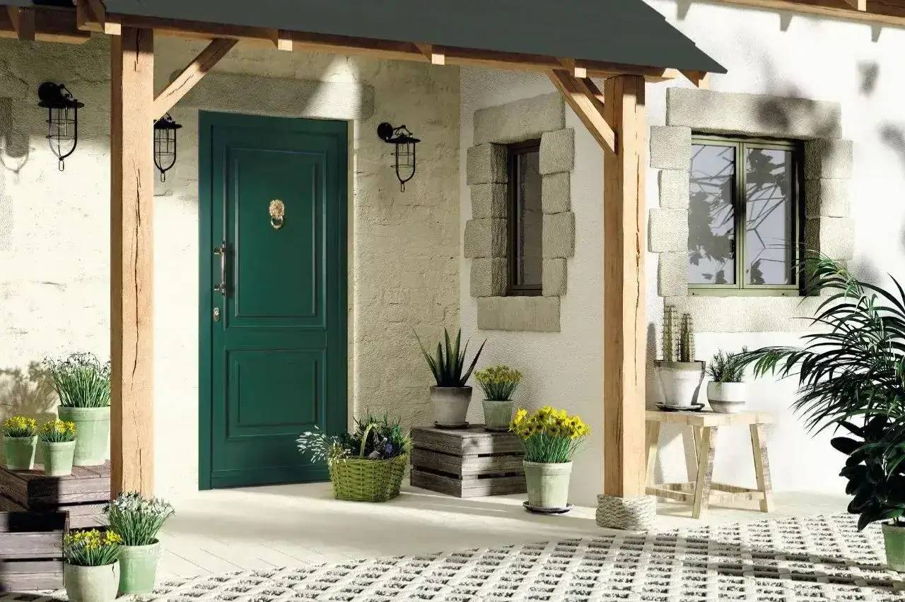 Une entrée accueillante avec une porte verte, entourée de plantes en pot et de décorations rustiques sous un auvent en bois.