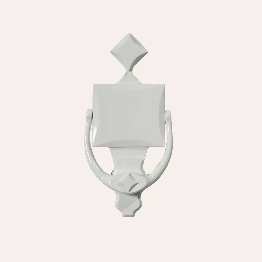 Un heurtoir de porte blanc, au design classique et élégant, reposant sur un fond beige clair.