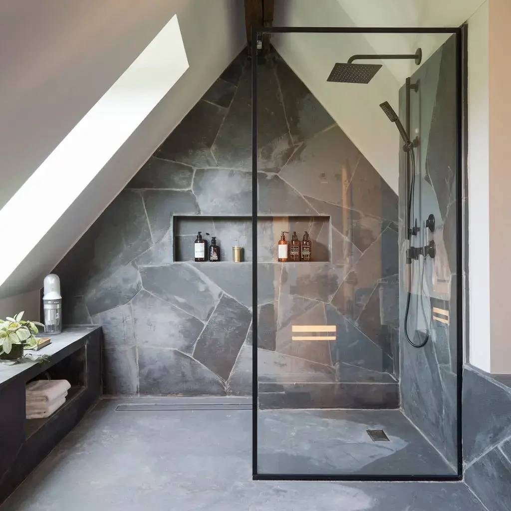 Douche moderne avec paroi en verre, carrelage en ardoise et niche intégrée pour les produits de bain.