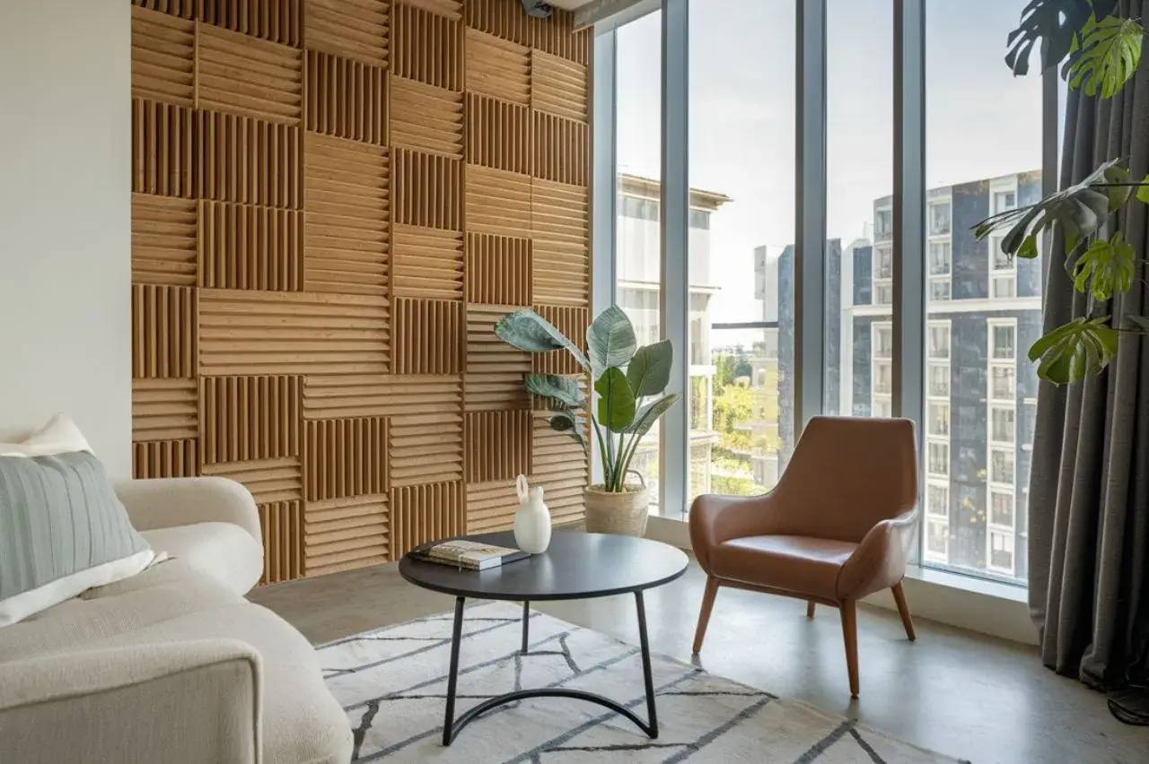 Un salon moderne avec un mur en bois texturé, de grandes fenêtres, et un décor minimaliste comprenant un fauteuil en cuir et une table basse noire