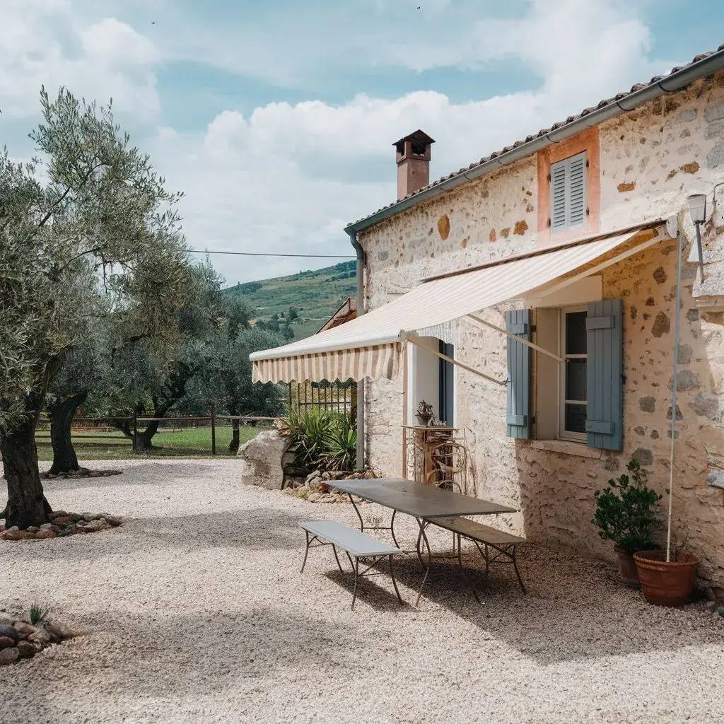 Une maison en pierre avec des volets bleus et un auvent rayé, entourée d'oliviers dans un cadre champêtre.