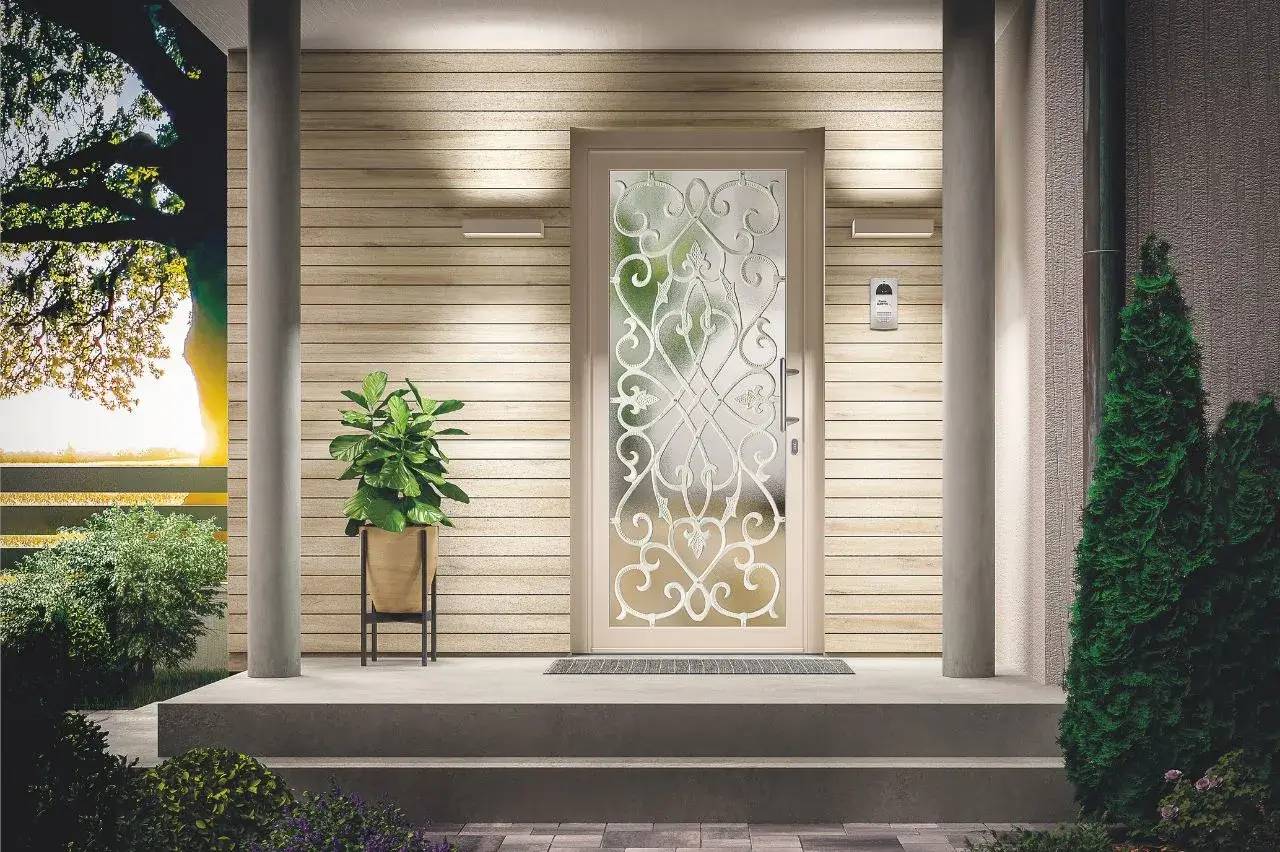 Entrée moderne avec une porte vitrée ornée de motifs décoratifs, entourée d'une végétation luxuriante et d'un mobilier élégant.