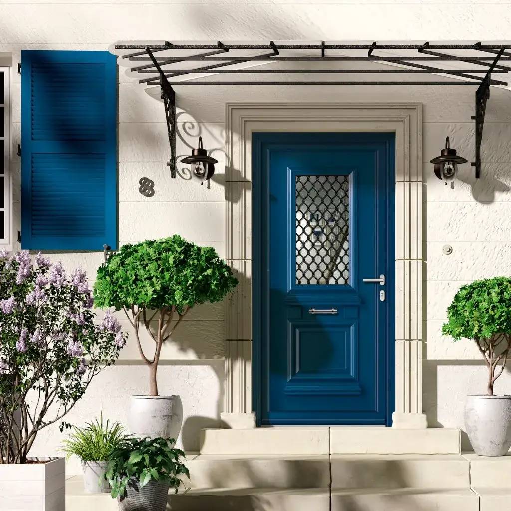 Entrée élégante avec une porte bleue ornée d'un auvent en fer forgé et entourée de plantes en pot.