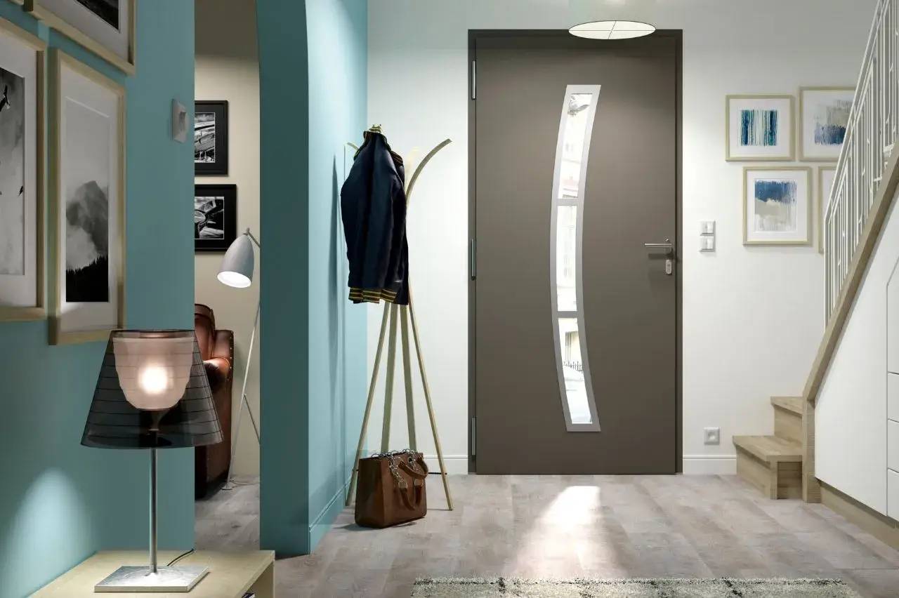 Entrée moderne avec une porte grise design, un sol en bois clair et des murs bleu pastel, agrémentée de décorations murales et