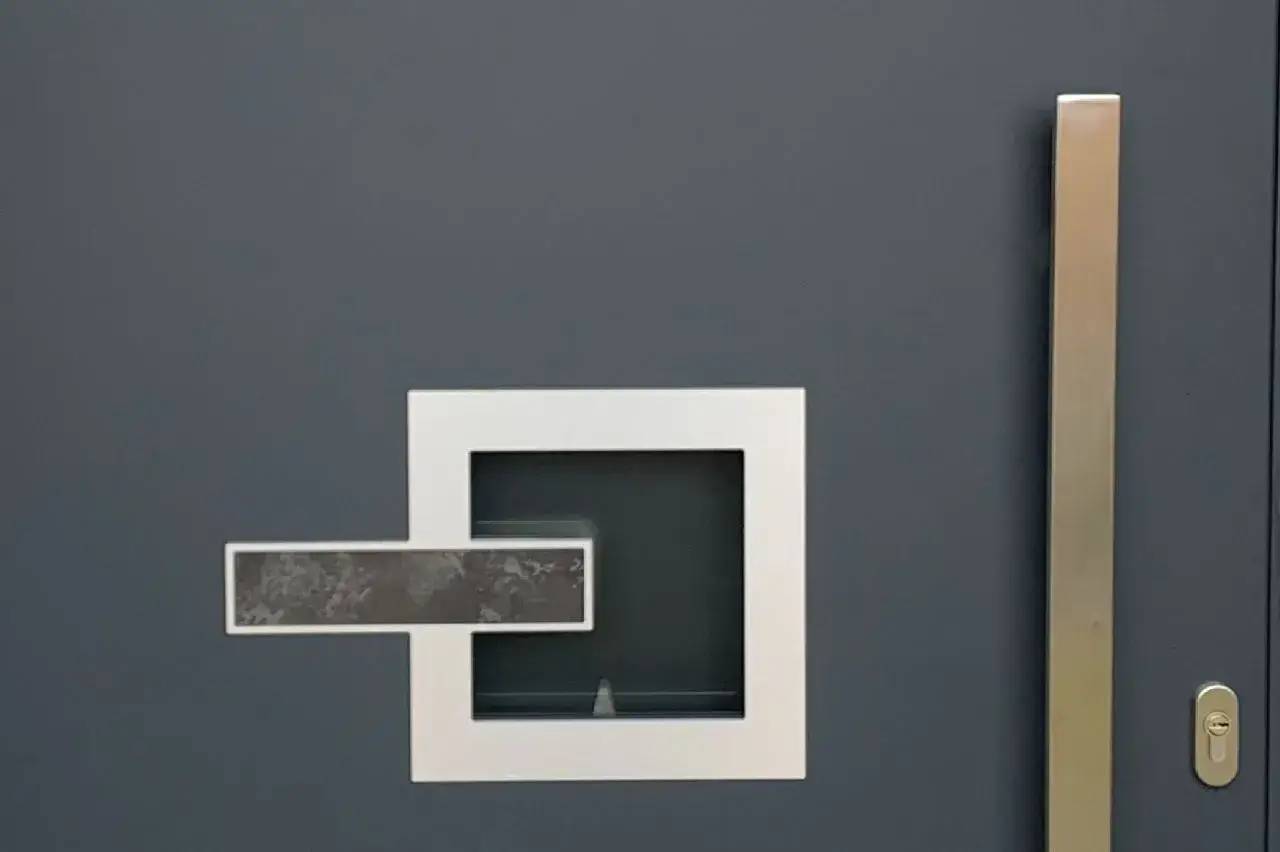 Porte moderne grise avec poignée et insert carré en métal blanc.