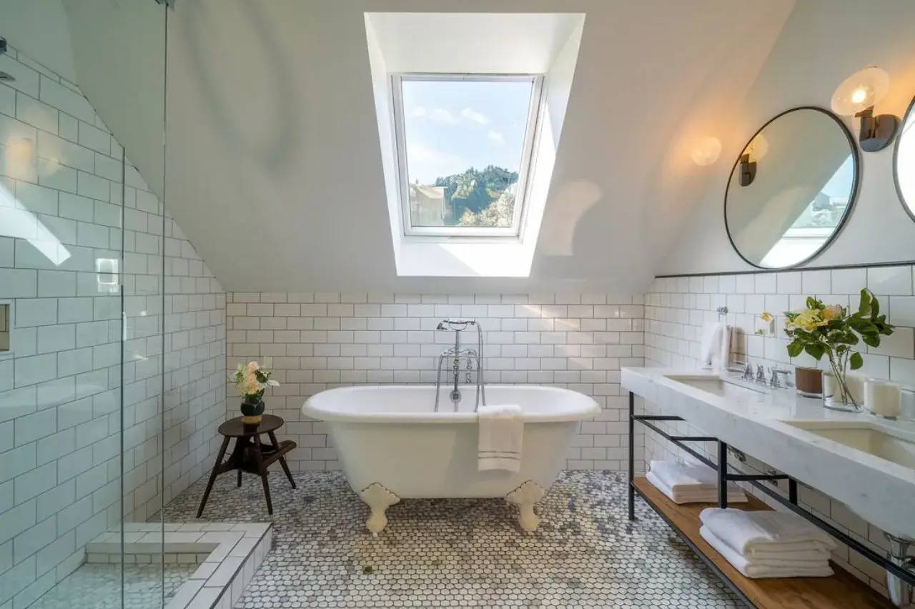 Salle de bain moderne et lumineuse avec baignoire îlot, carrelage hexagonal, et puits de lumière.