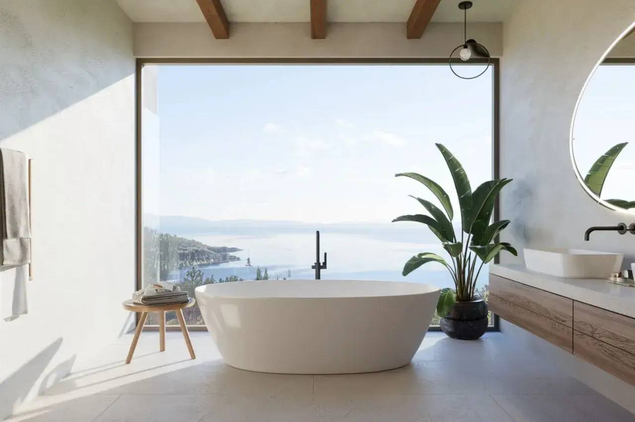 Une salle de bain moderne avec une baignoire blanche en îlot, offrant une vue panoramique sur l'océan grâce à une large baie vitrée