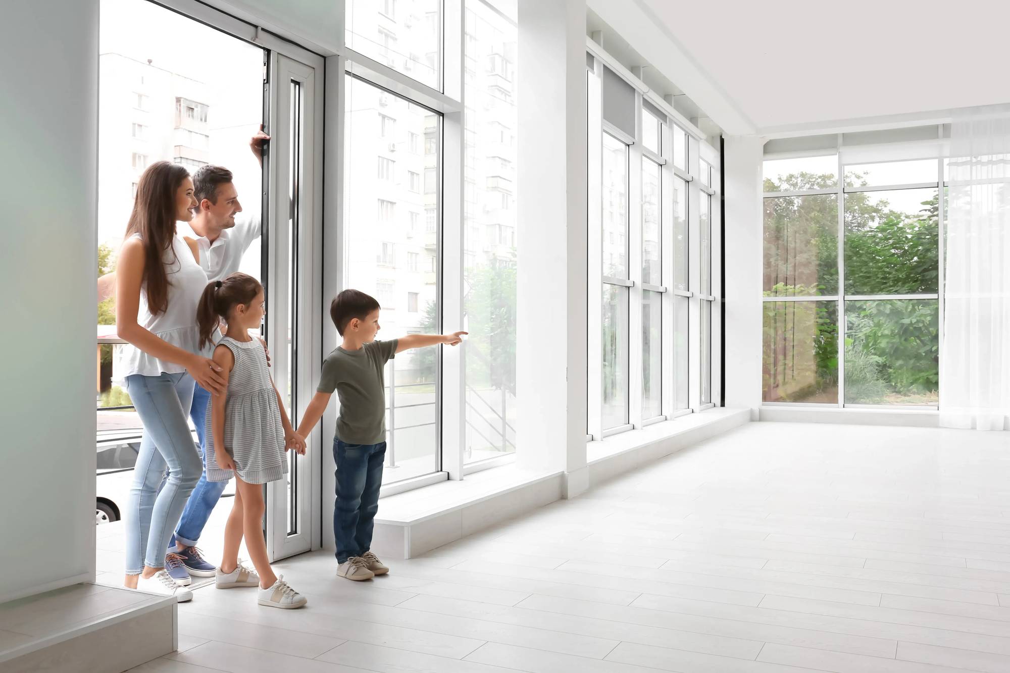 Une famille observe l'intérieur lumineux d'une maison moderne avec de grandes fenêtres.