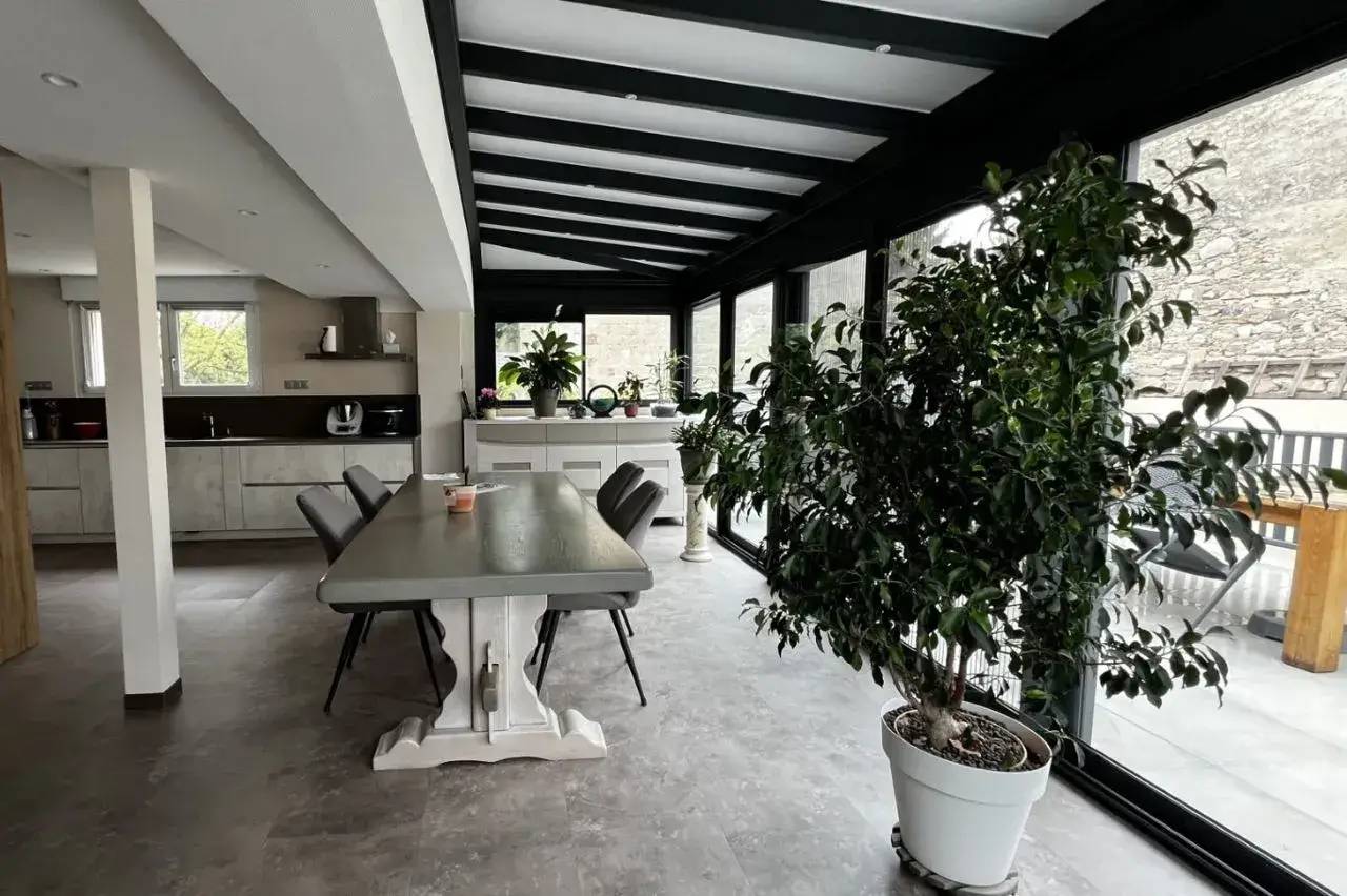 Salle à manger lumineuse et moderne, agrémentée de grandes baies vitrées et de plantes vertes.