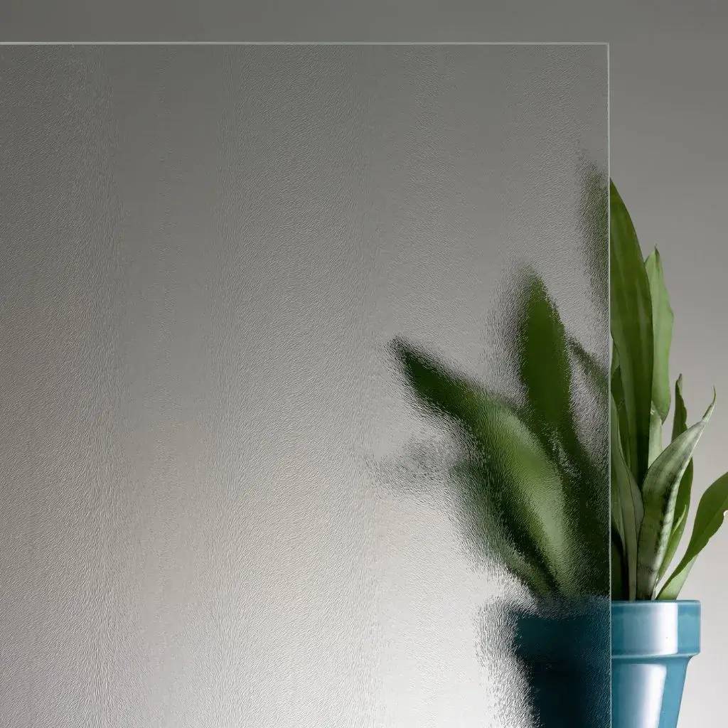 Verre texturé semi-transparent avec un pot de plante verte en arrière-plan flou.