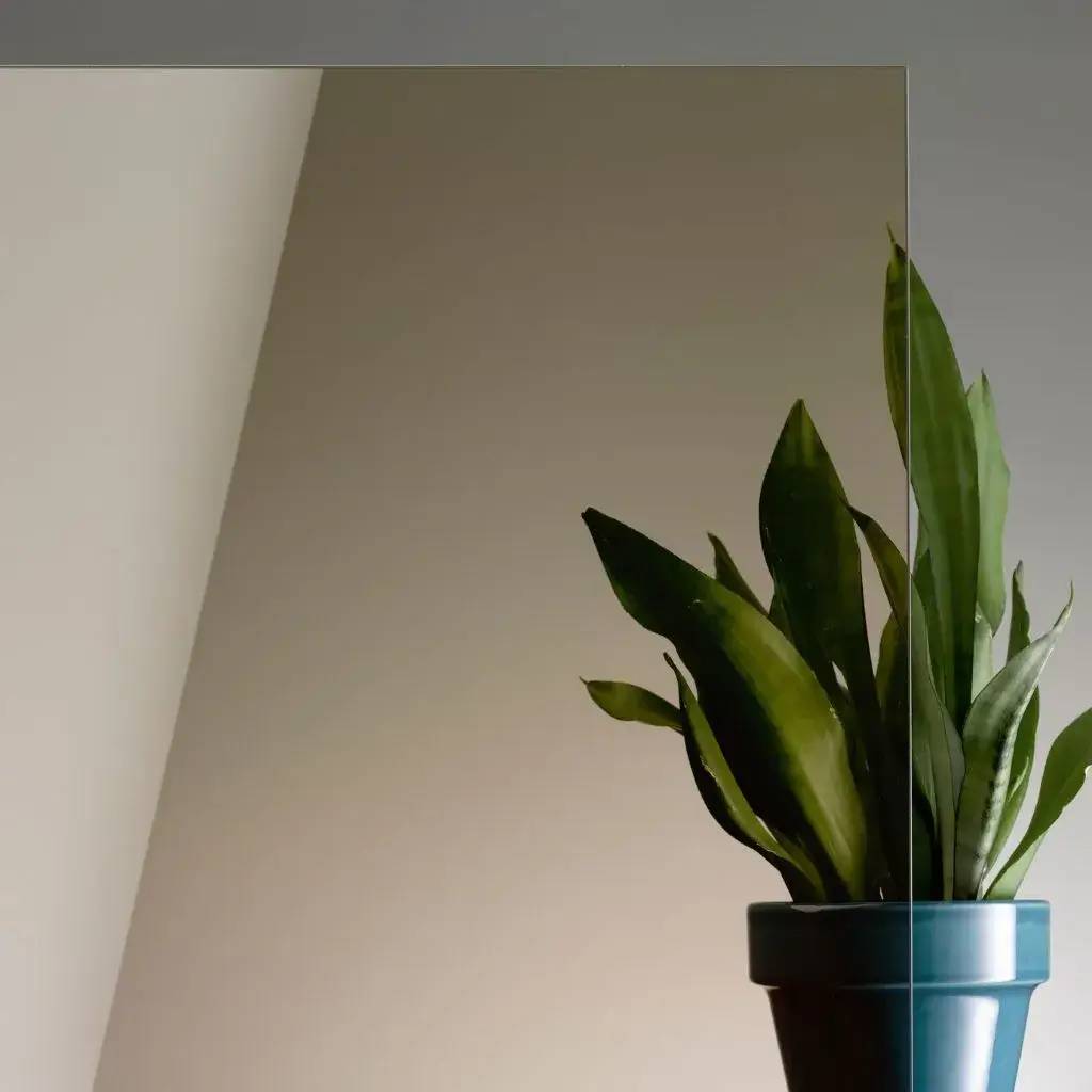 Une plante verte dans un pot bleu se reflète élégamment dans un miroir, créant une composition minimaliste.