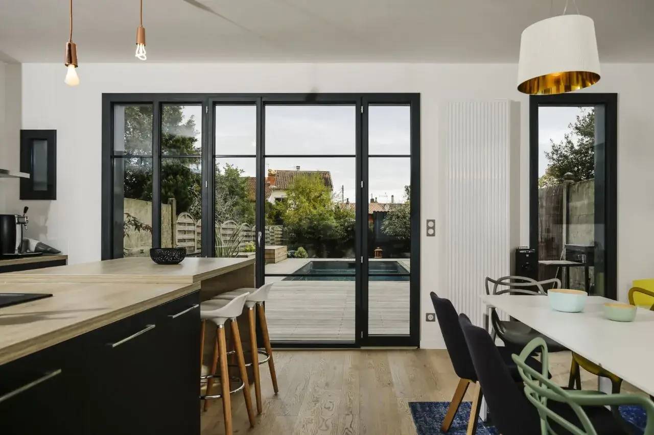 Une cuisine moderne et lumineuse s'ouvre sur une terrasse avec piscine, offrant un cadre accueillant et élégant.