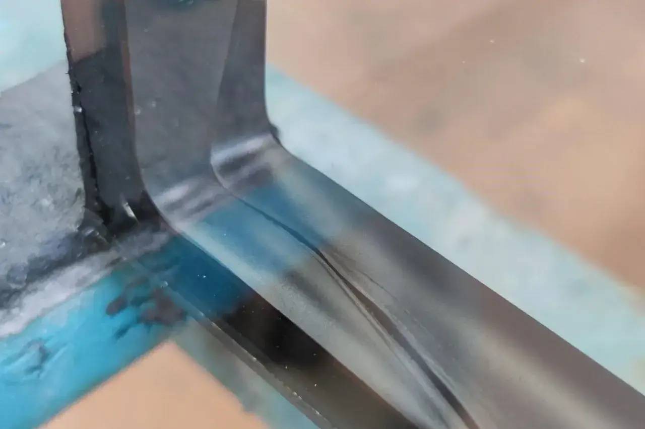 Une lame de couteau en gros plan, avec un reflet métallique et un fond flou.