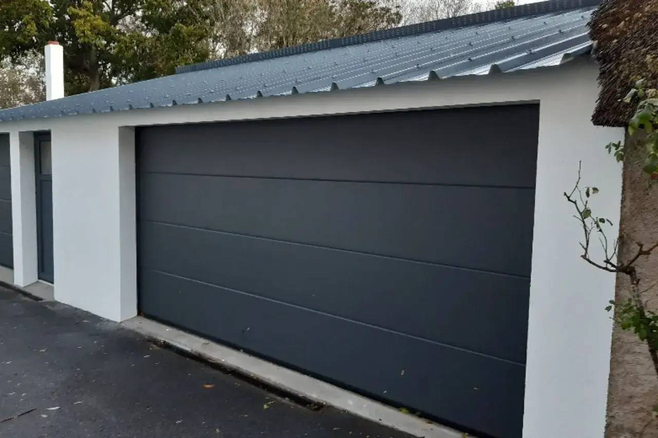 Porte de garage moderne en métal gris anthracite avec toit en tôle ondulée.
