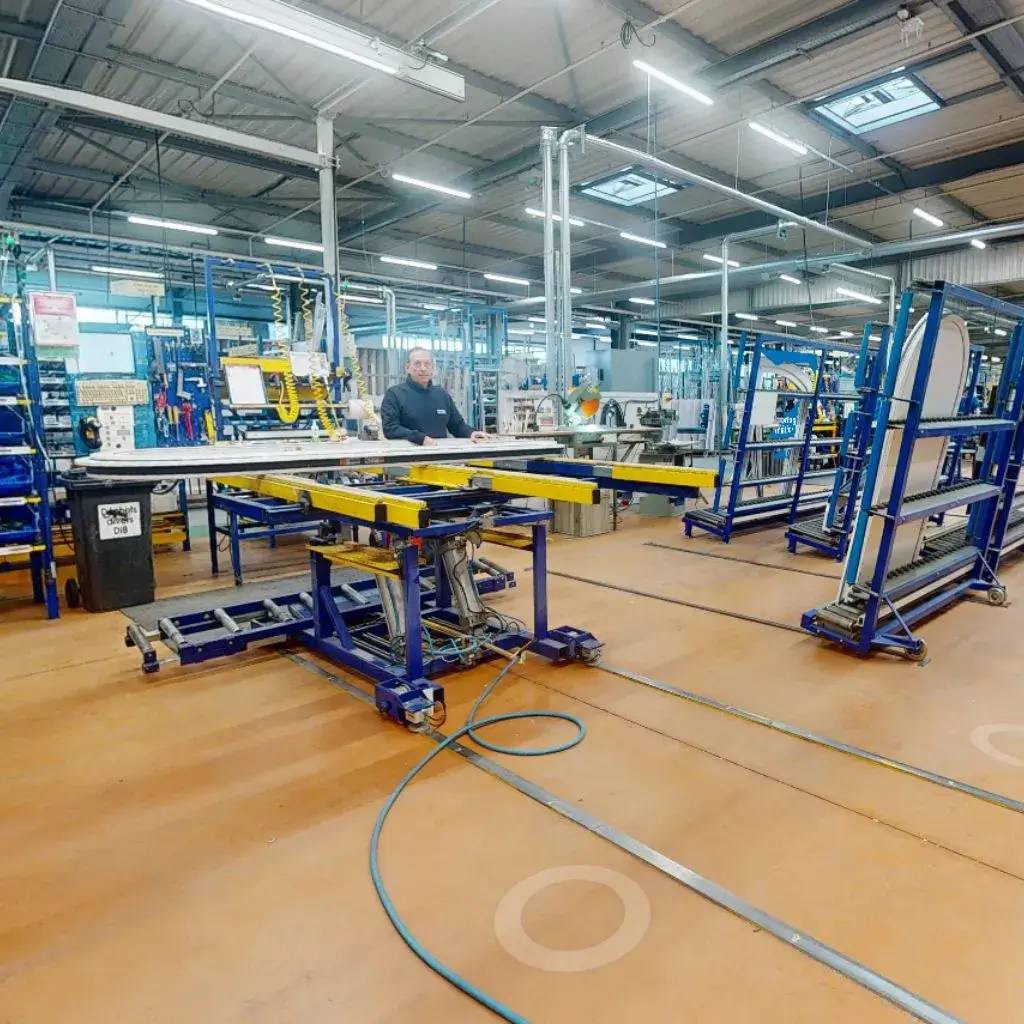 Une usine moderne avec un ouvrier travaillant sur une machine entourée de structures métalliques et d'équipements industriels.