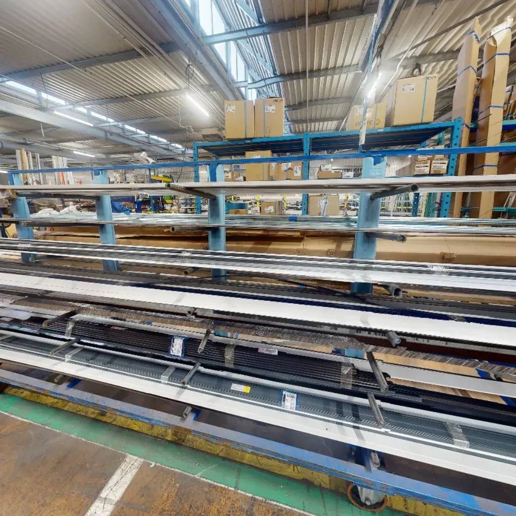 Un entrepôt industriel bien éclairé abrite des étagères métalliques chargées de divers matériaux de construction et de cartonages entreposés